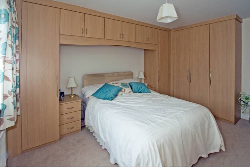 bedroom with custom-built overbed cupboards and wardrobes in pine colour